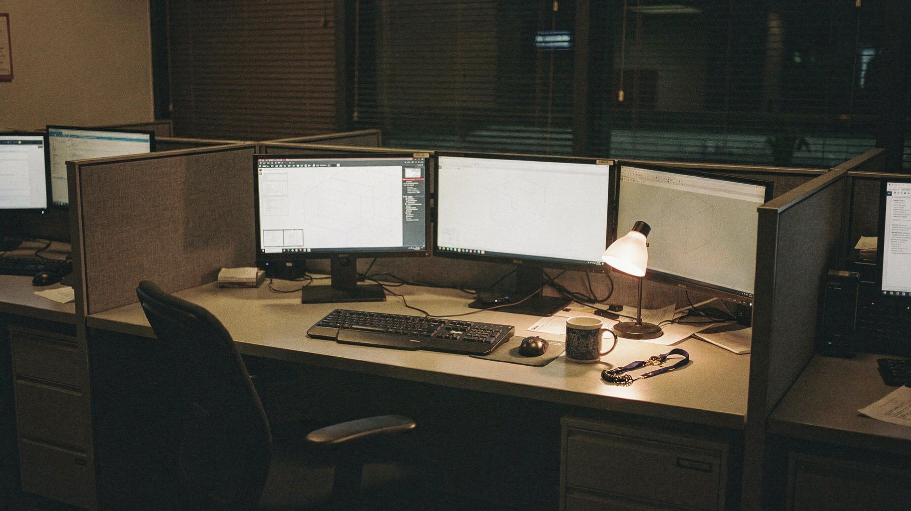 A documentary photograph of an empty security operations desk at night, several monitors glowing with faint world-map wireframes, a coffee mug and a lanyard left beside the keyboard, chair pushed back, nobody in frame