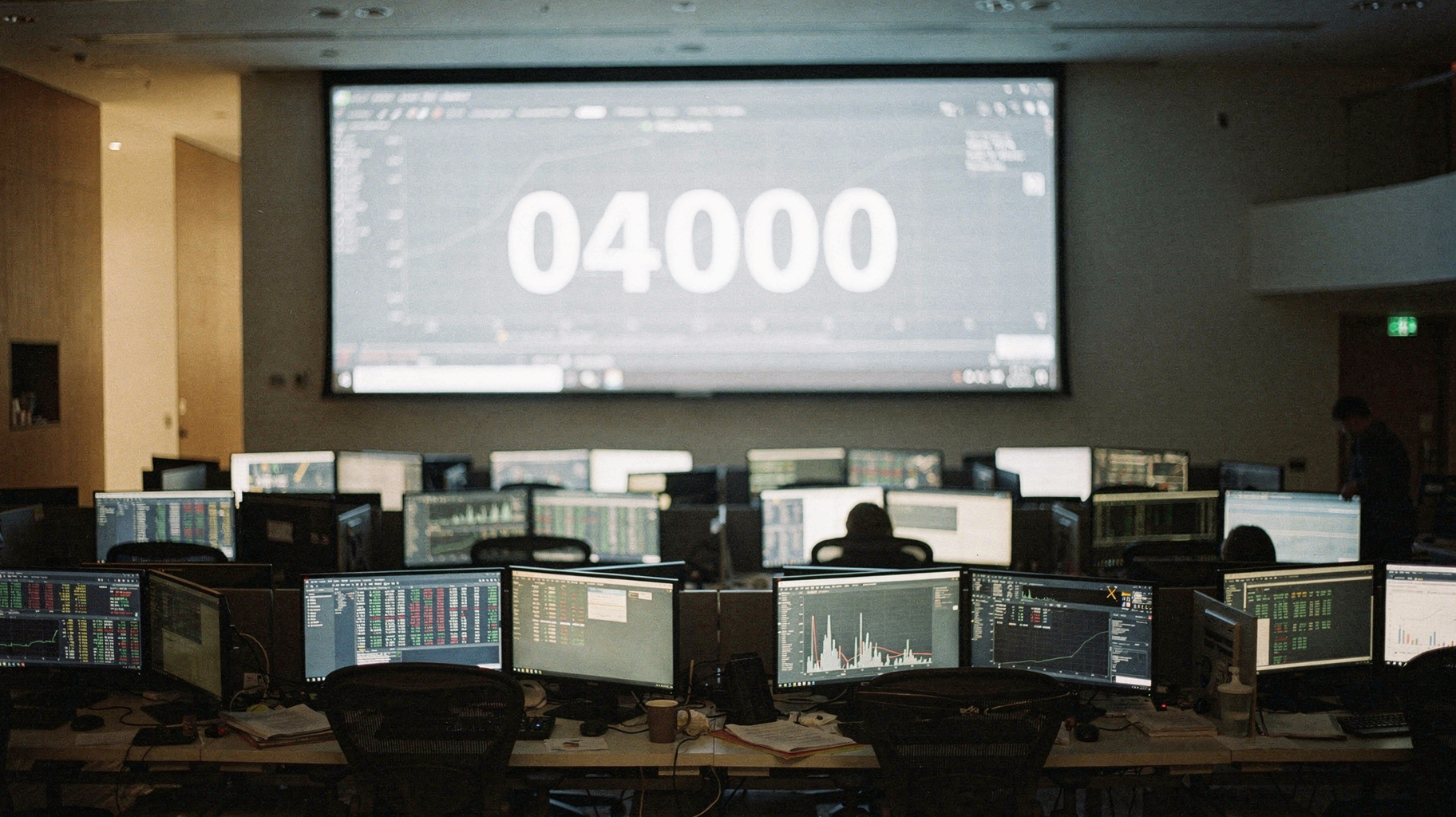 A trading floor with a single enormous figure glowing on a wall display, empty desks in the foreground